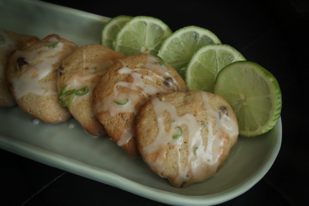 key lime chocolate chip cookies with icing on a green oblong plate with limes