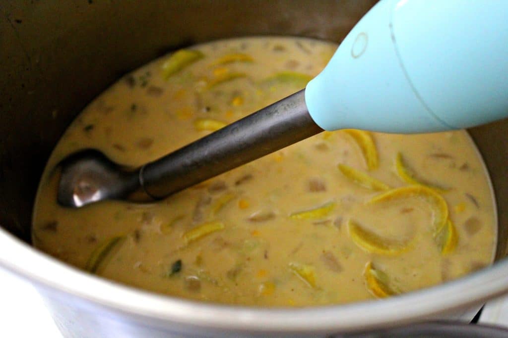 Squash Chowder Soup in a large pot on the stove with an immersion blender blending it up