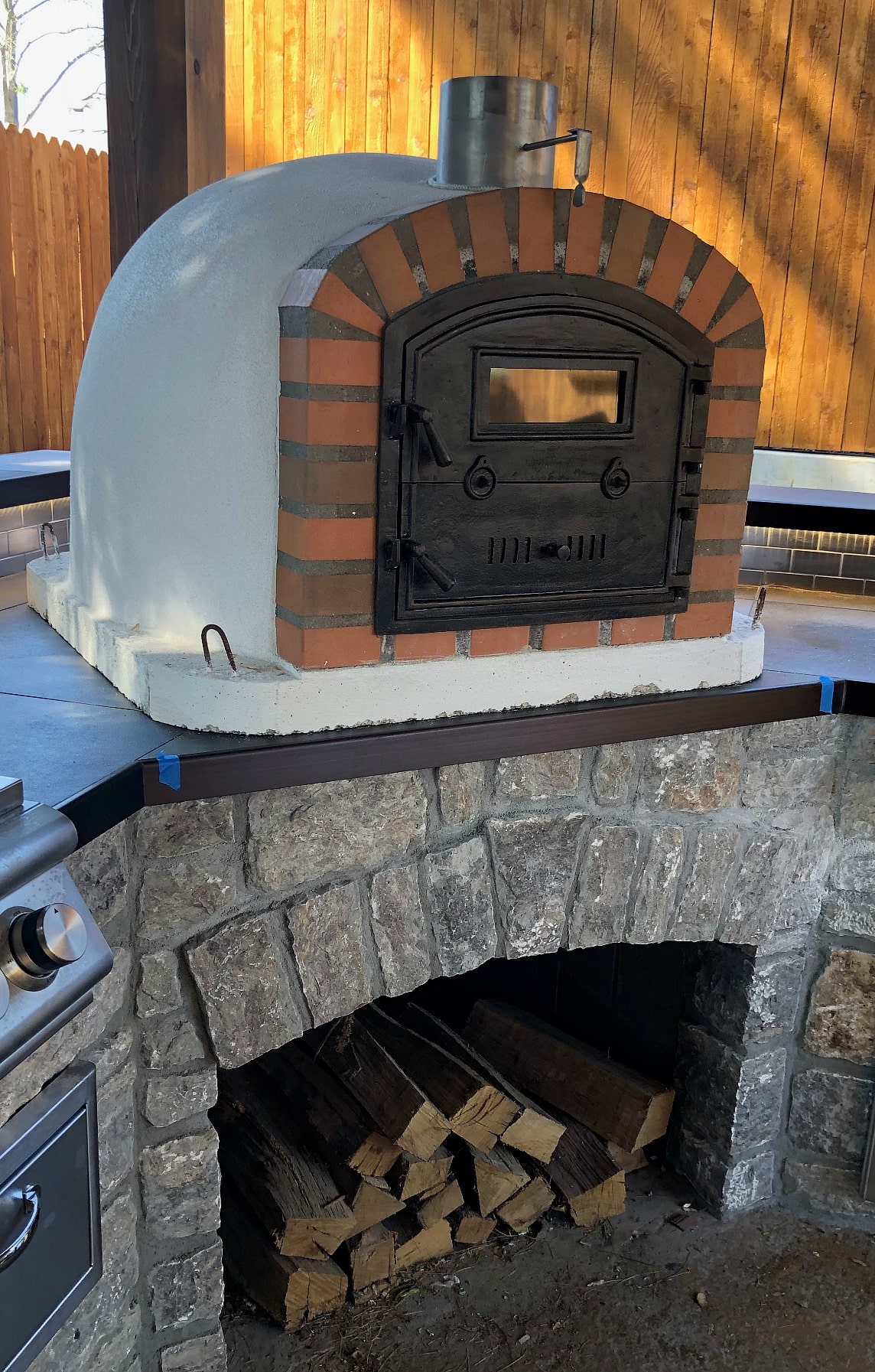 Installed pizza oven on top of counter with firewood underneath