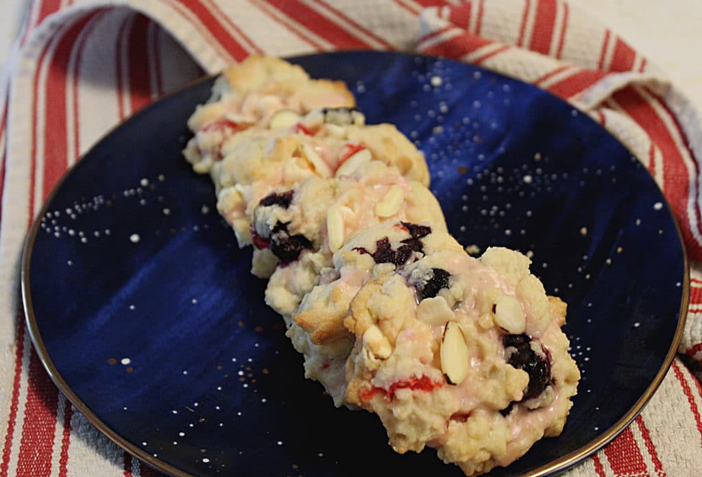 cherries and blueberries almond cookies on blue space plate