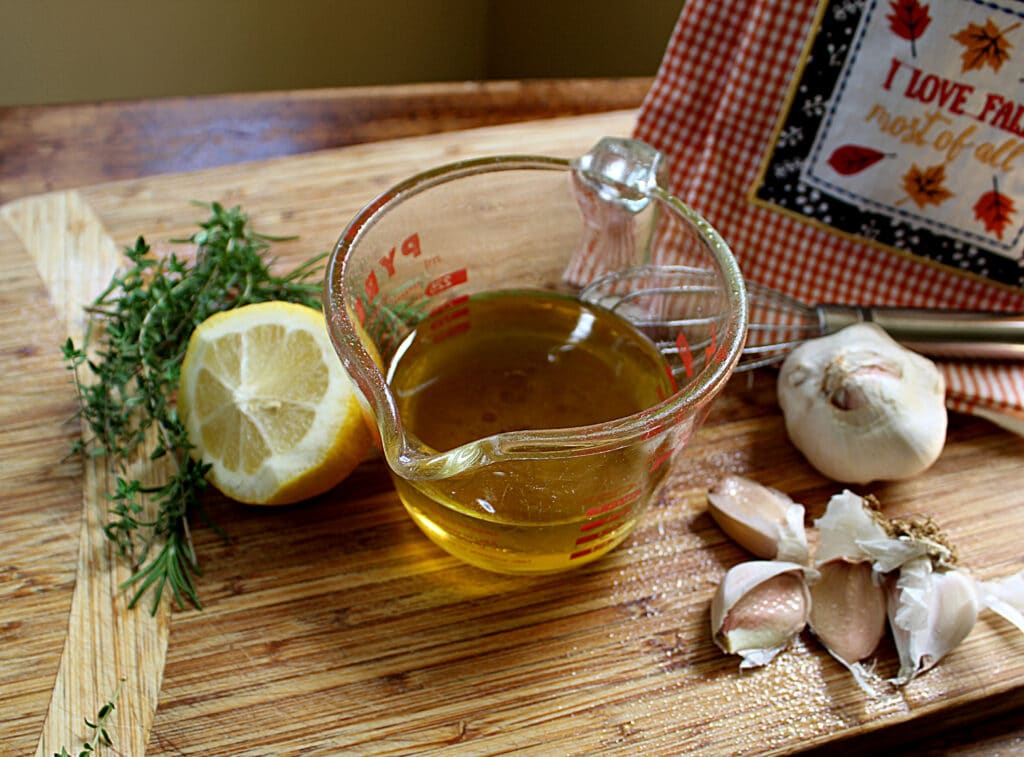 Olive oil, lemon, garlic, thyme, whisk on a cutting board