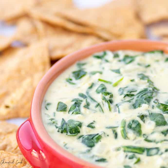 Warm Spinach Dip in a red bowl on a platter with chips