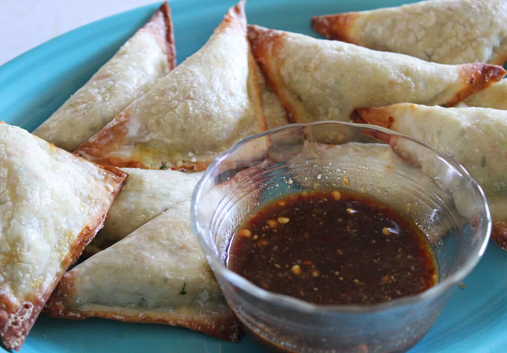 Spicy crab wontons with sweet mustard sauce on a blue plate