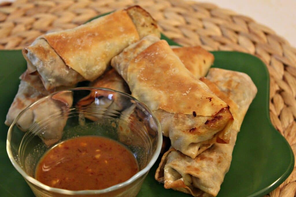 Baked shrimp eggrolls with spicy sauce on a green plate