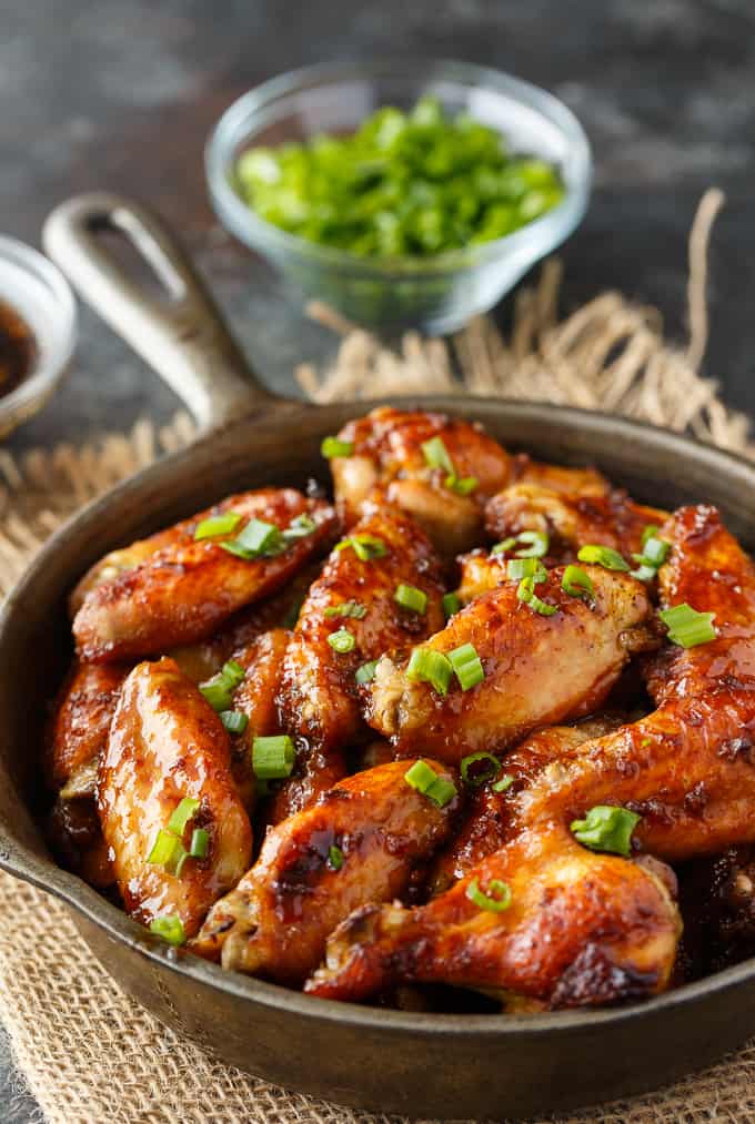 oven baked chicken wings in a cast iron skillet on a burlap plate mat