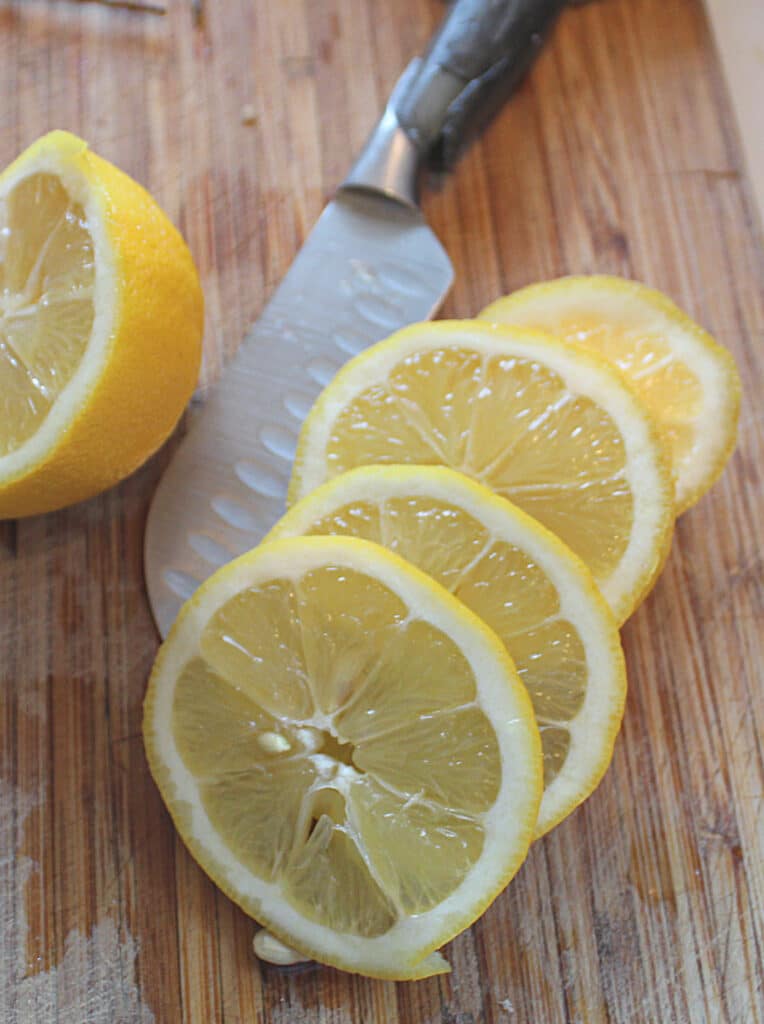 sliced lemon on a cutting board with a knife