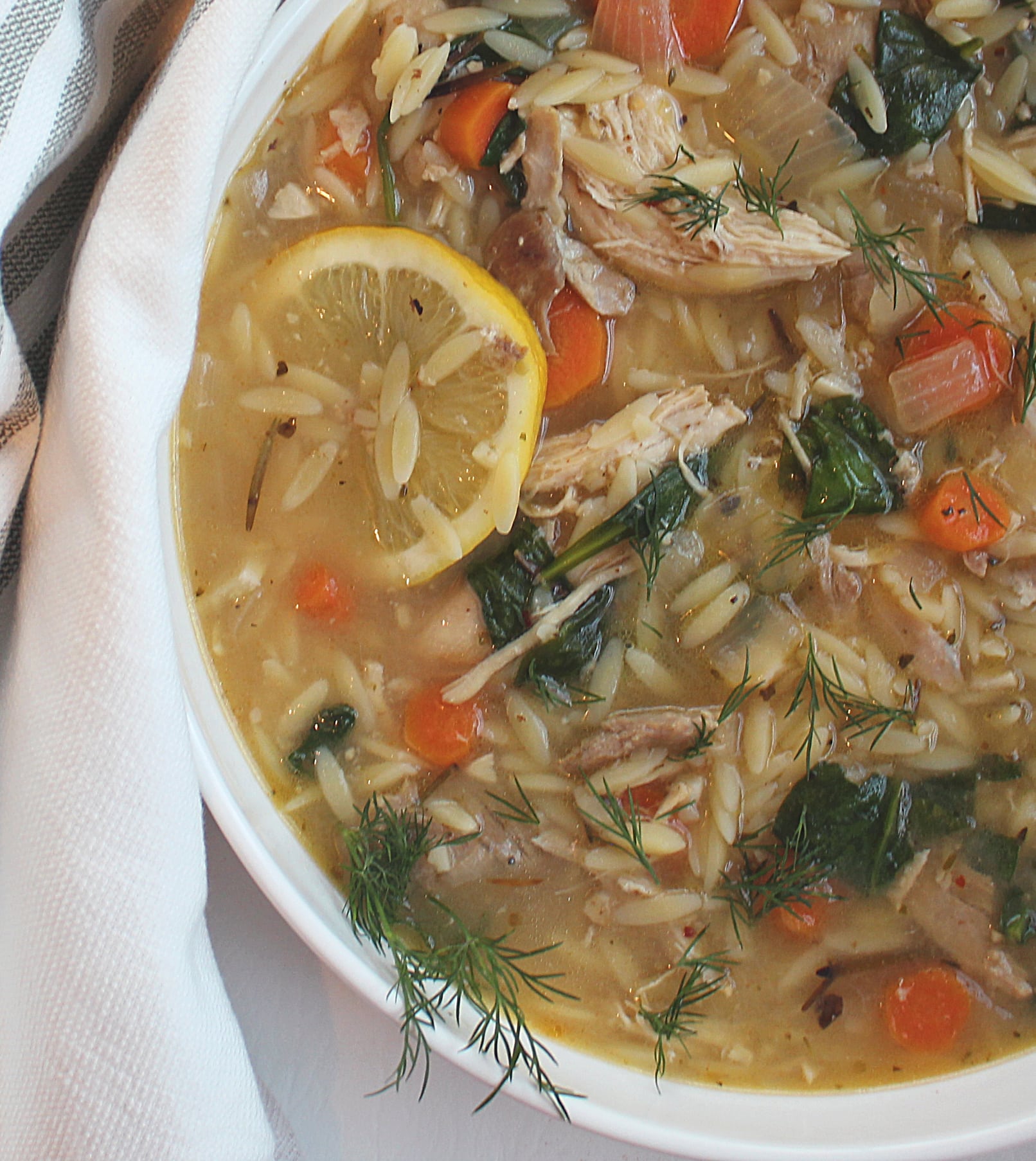 lemon chicken orzo soup in a white serving bowl