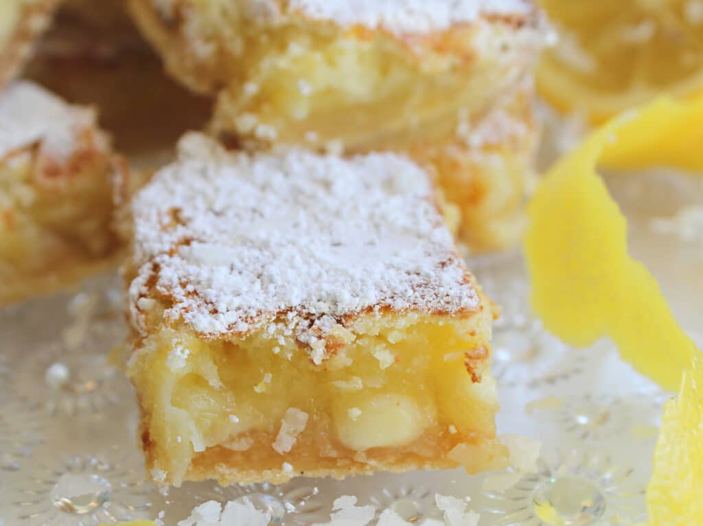 single lemon bar with coconut and white chocolate on a crystal serving tray