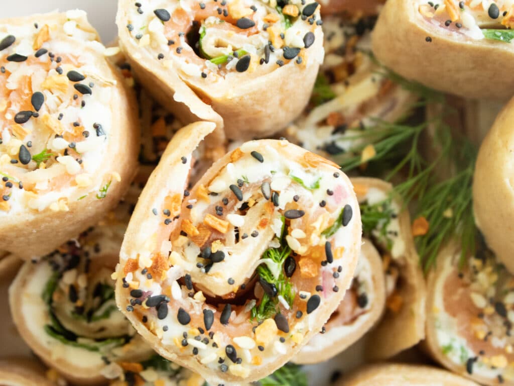 Close up of everything pinwheel with fresh dill and everything bagel seasoning sprinkled on top.