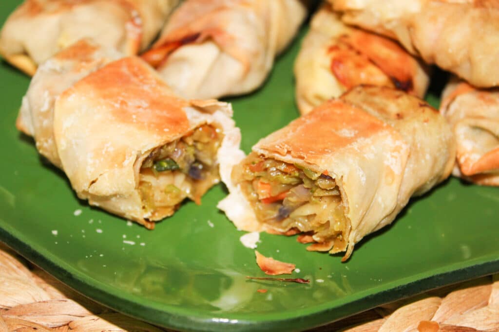 Close up of a shrimp eggroll cut in half on a green plate