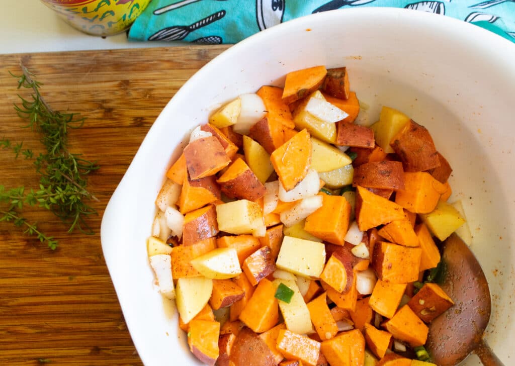 Raw sweet potato hash on a butcher block in a white mixing bowl>