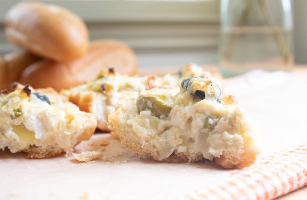 close up of several pieces of bread with whole loaves of bread in the background