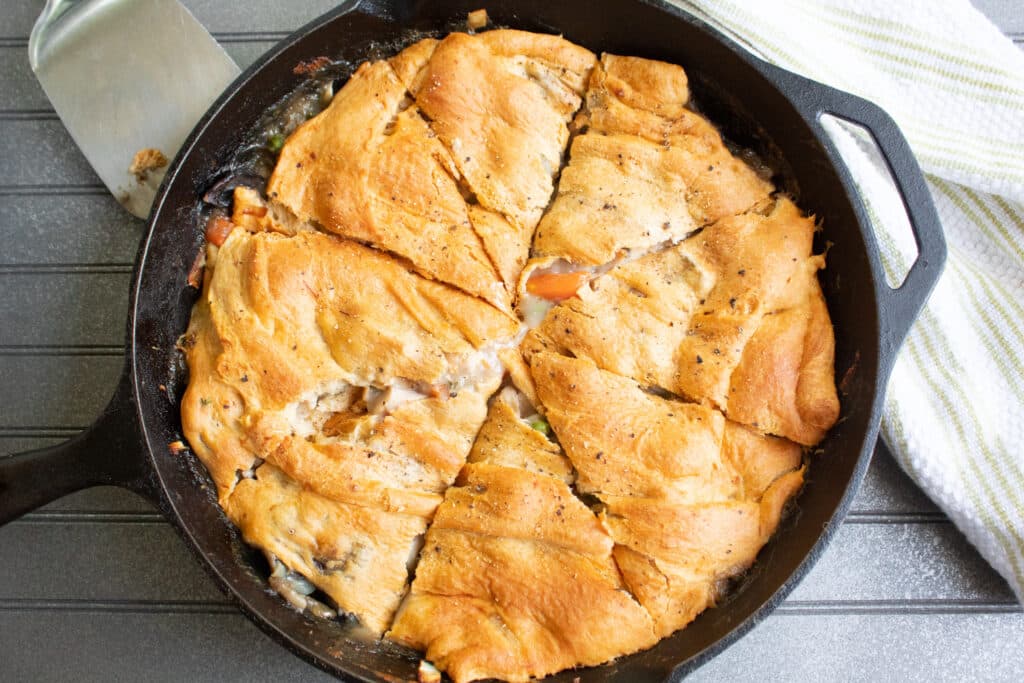 Golden Easy Chicken Pot Pie cut pie style in a cast iron skillet