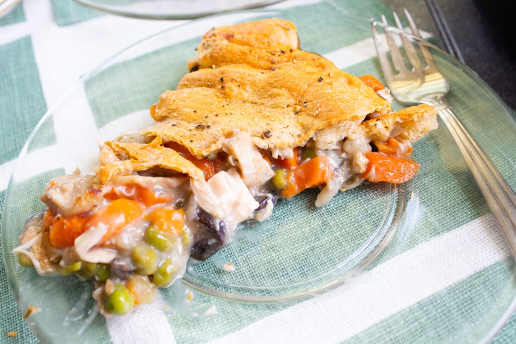 single piece of chicken pot pie on a clear plate with a fork