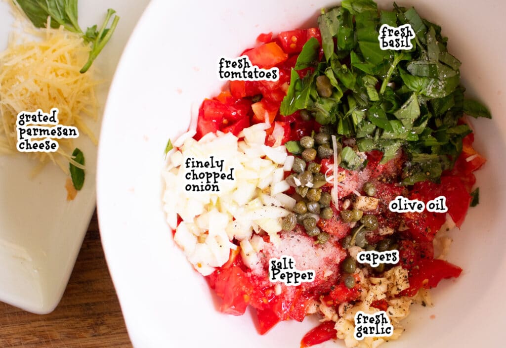 cut up ingredients of garden fresh tomato basil bruschetta in a white bowl with labels