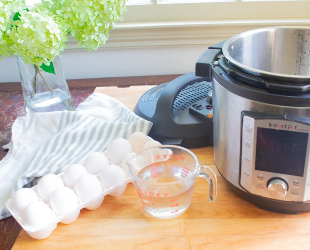 Ingredients and instant pot on a cutting board with flowers in the background