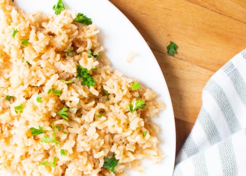 overhead close up of baked rice with parsly on a white plate with a gray and white striped