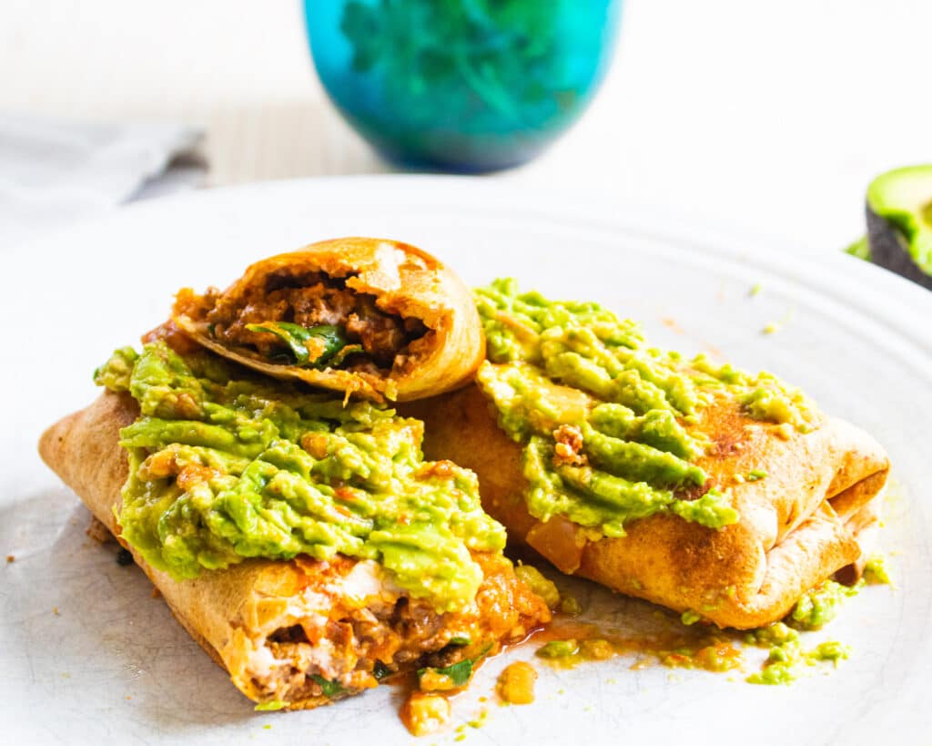 air fryer crunchy burritos with spicy avocado on a white plate