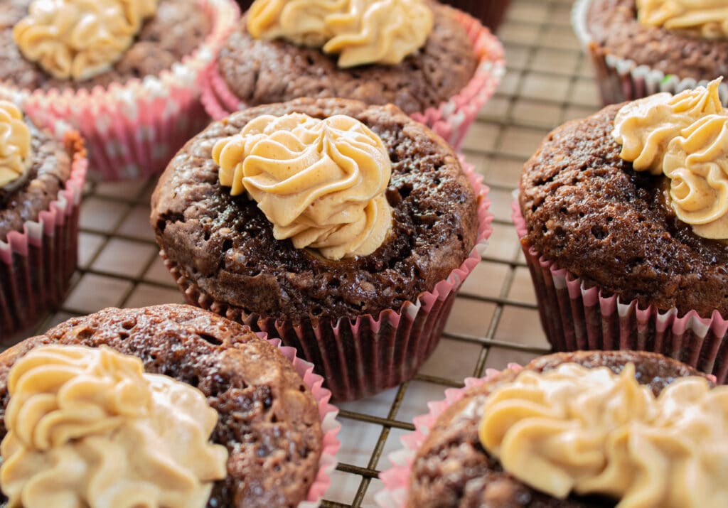 Several banana brownies with peanut butter frosting cupcakes on a wire rack.