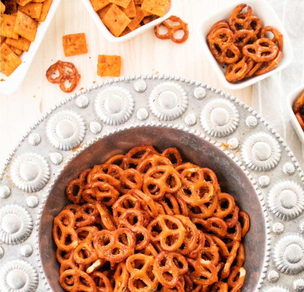 Overhead seasoned Italian pretzel recipe in a silver serving bowl with feisty cheddar mini crackers.