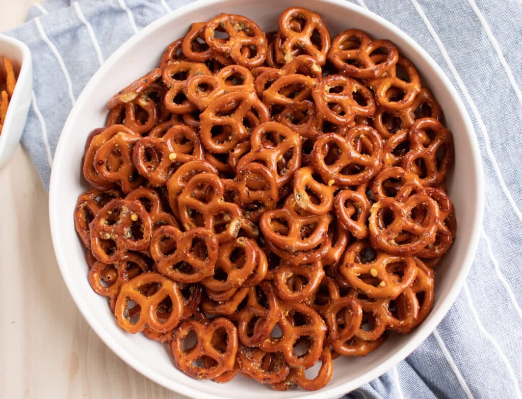 overhead zesty Italian seasoned mini pretzels in a white bowl on a blue towel.