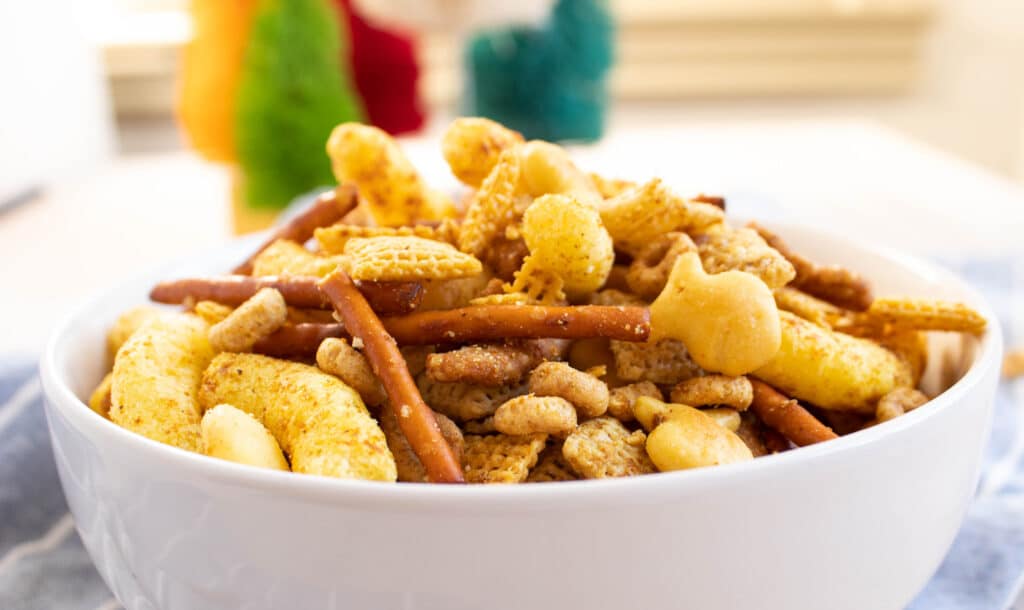 Curry Chex mix with sesame sticks and goldfish in a white bowl.