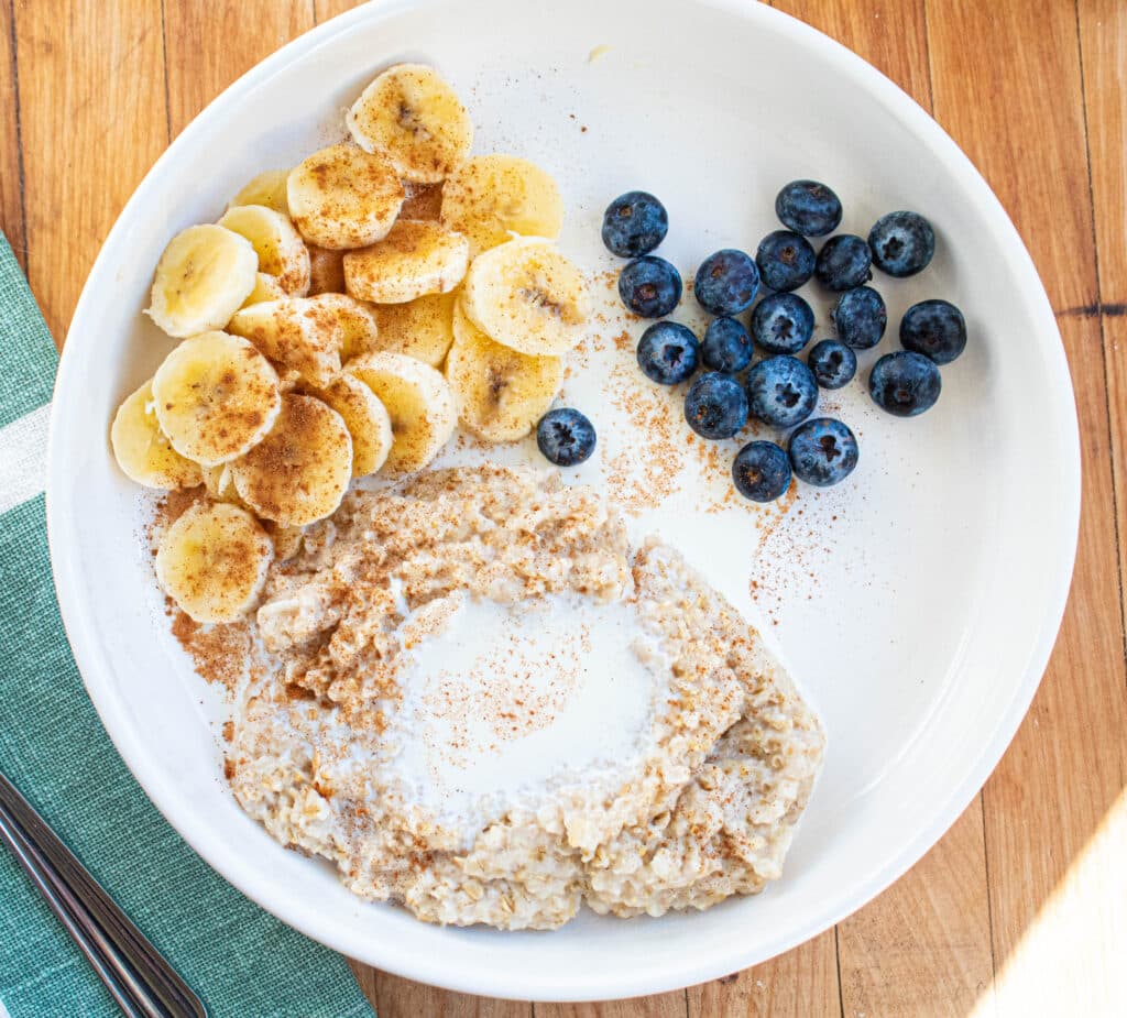 blueberry banana oatmeal breakfast with ingredients separated in a white bowl