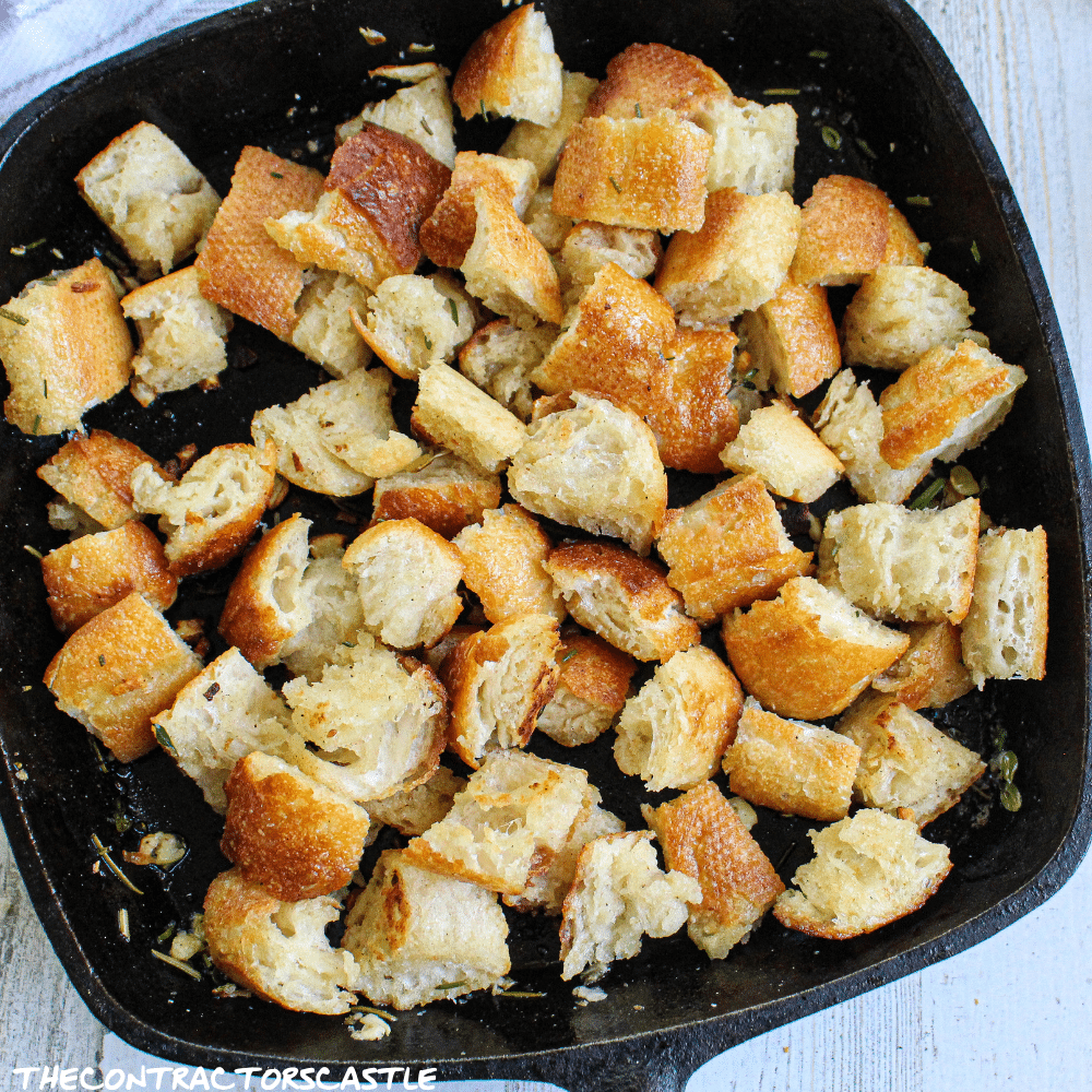 close up of stove top golden croutons in a cast iron skillet.