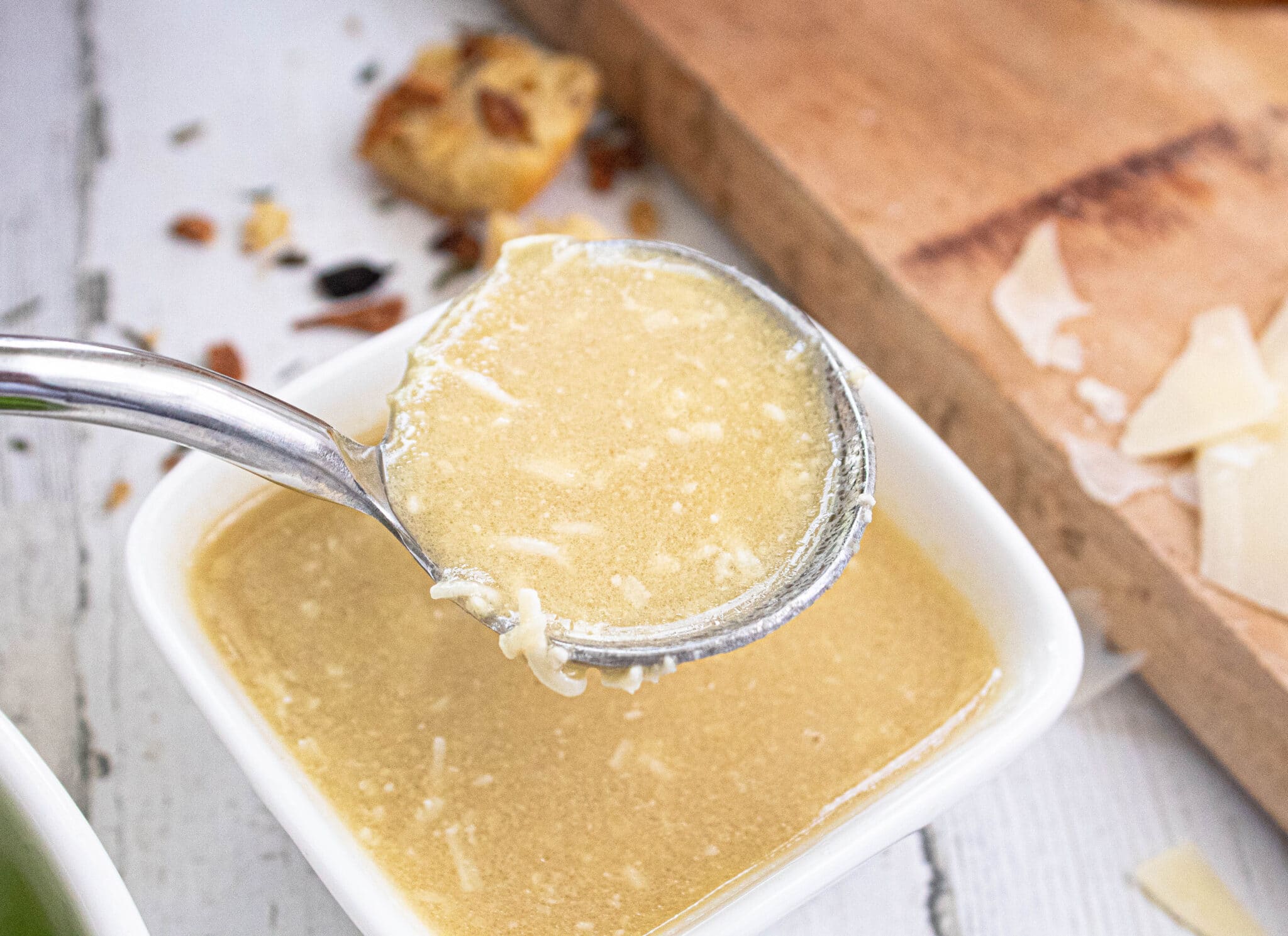 Spoonful of homemade Caesar Salad Dressing over a white square bowlful of Caesar Dressing