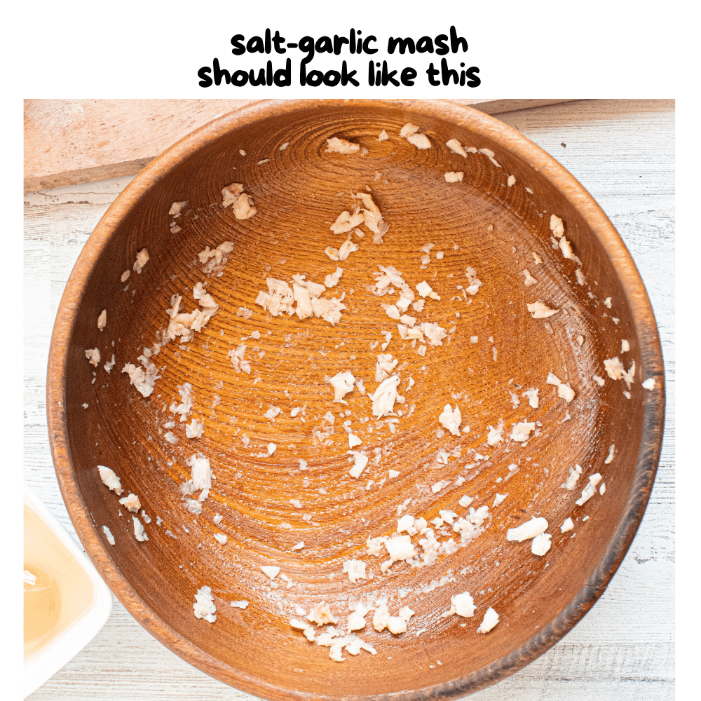 smashed garlic and coarse sea salt rubbed all around inside of wooden bowl.