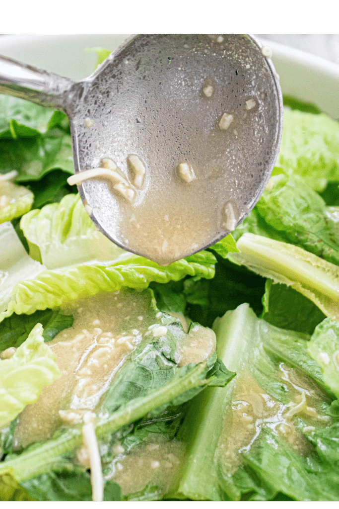 close up of dressing being spooned on bite size romaine lettuce leaves.