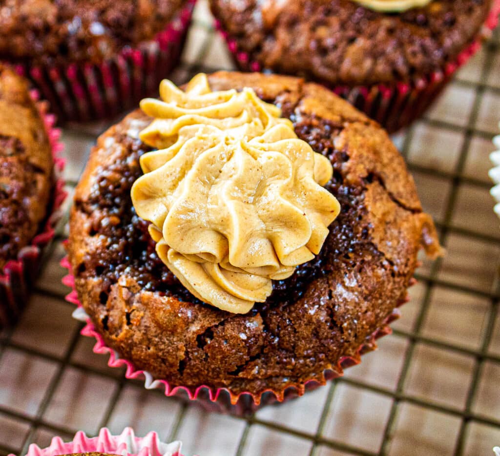 Overhead of a complete banana brownie cupcake with peanut butter frosting on a cooling rack.