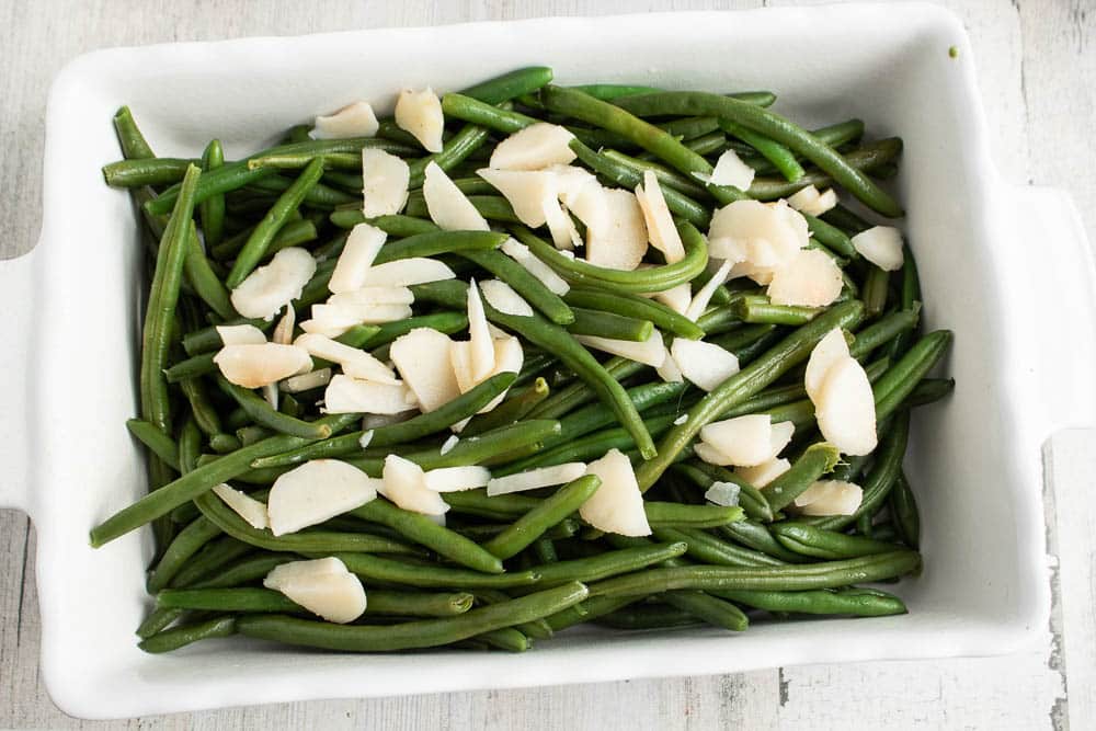 Blanched green beans and sliced water chestnuts in a white rectangle casserole dish.