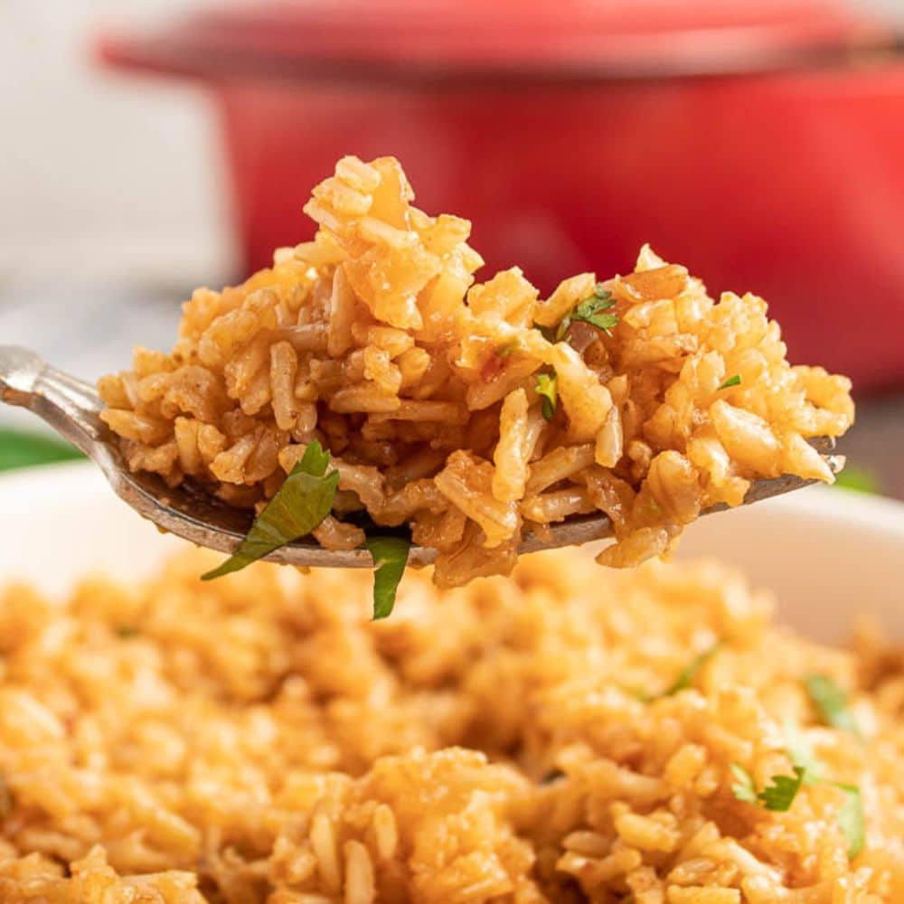 Side view of a fork full of easy Mexican baked rice over a big bowl of rice.