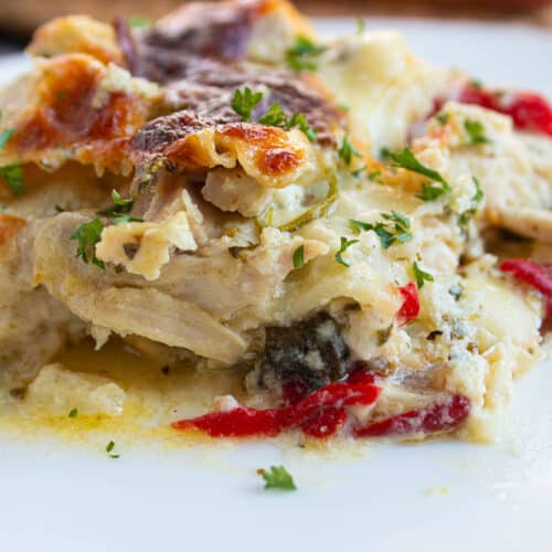 Single serving of White Chicken Lasagna with Spinach and Roasted Red Peppers on a white plate.