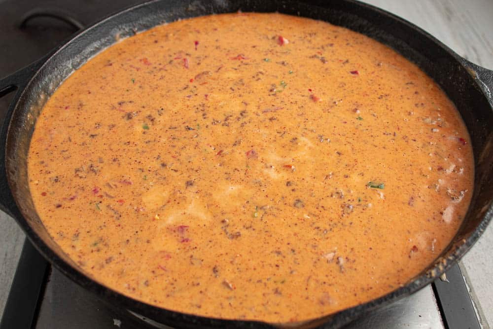 Finished spicy sausage Rotel Queso Cheese Dip in a cast iron skillet.