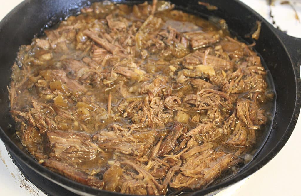 Done Juicy Slow Cooked Pulled Beef in a cast iron skillet.