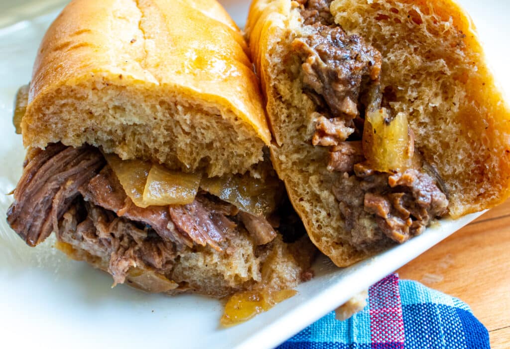 Drip Beef Sandwiches cut in half on a white plate.