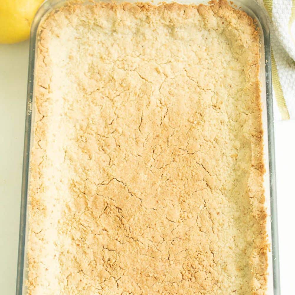 Almond shortbread crust in a glass 9x13 pan after it's baked.