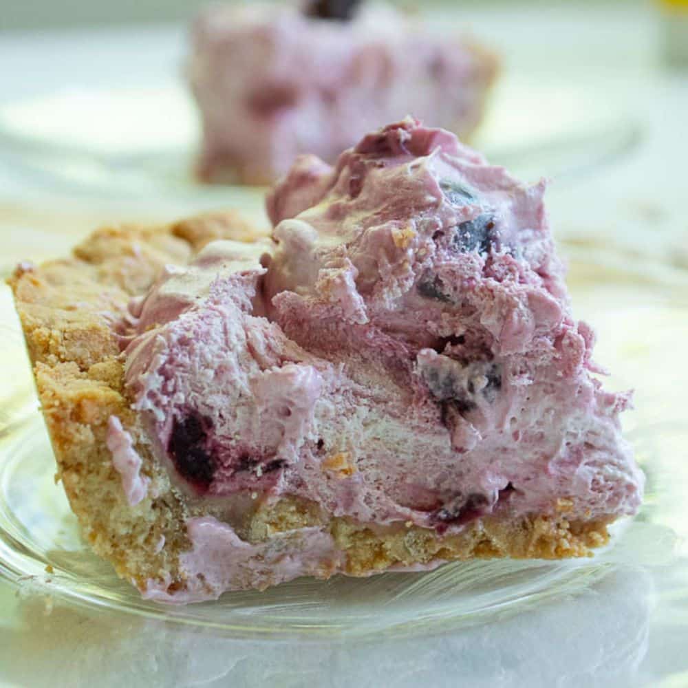 Side view of a piece of chocolate cherry fluff bars with shortbread crust on a glass dessert plate.