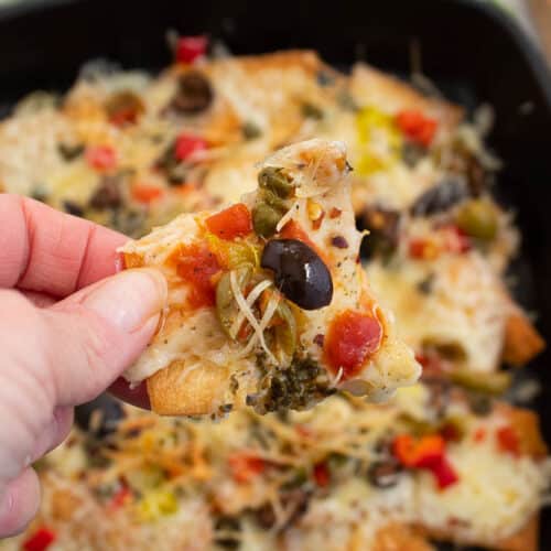 1 Italian nacho over a pan full of Italian nachos.