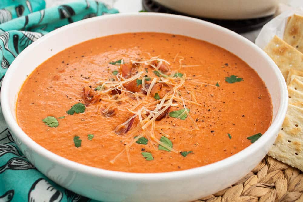 Homemade Bacon Tomato Soup with bacon pieces, parmesan cheese, and parsley in a white soup bowl.