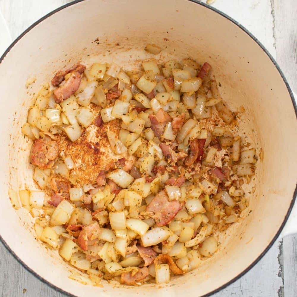 Bacon, onions, garlic, seasonings in a white Dutch oven.