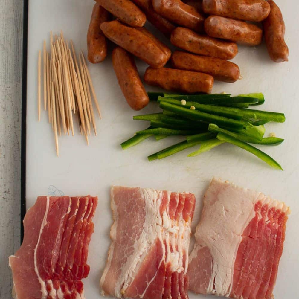 Brown sugar bacon wrapped little smokies ingredients on a white cutting board.