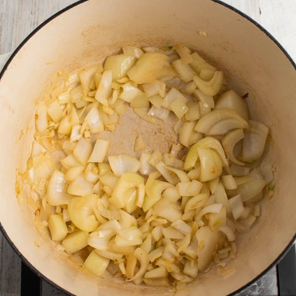 Onions and garlic sauteed in butter in a white Dutch oven.