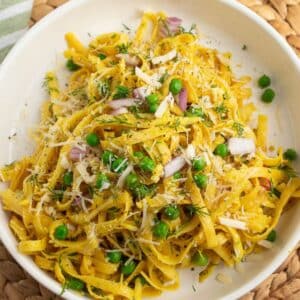 Curry Pasta with fresh dill and peas in a white bowl.