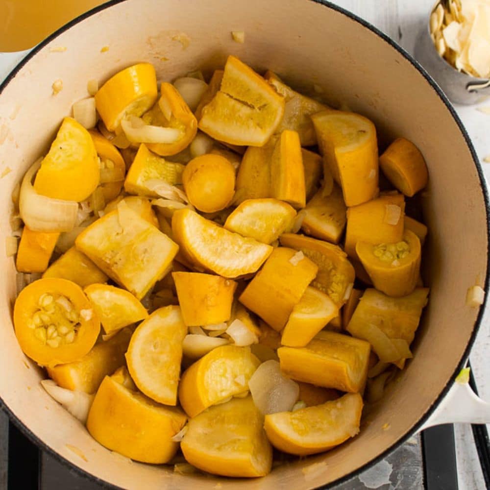 Squash,onions and garlic sauteed in butter in a white Dutch oven.