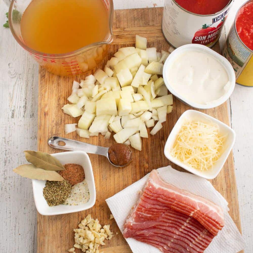 Homemade bacon tomato soup ingredients on a cutting board.