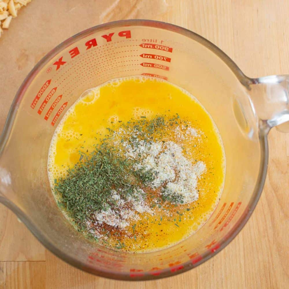 Whipped eggs, tarragon, garlic salt, nutmeg in a measuring cup.