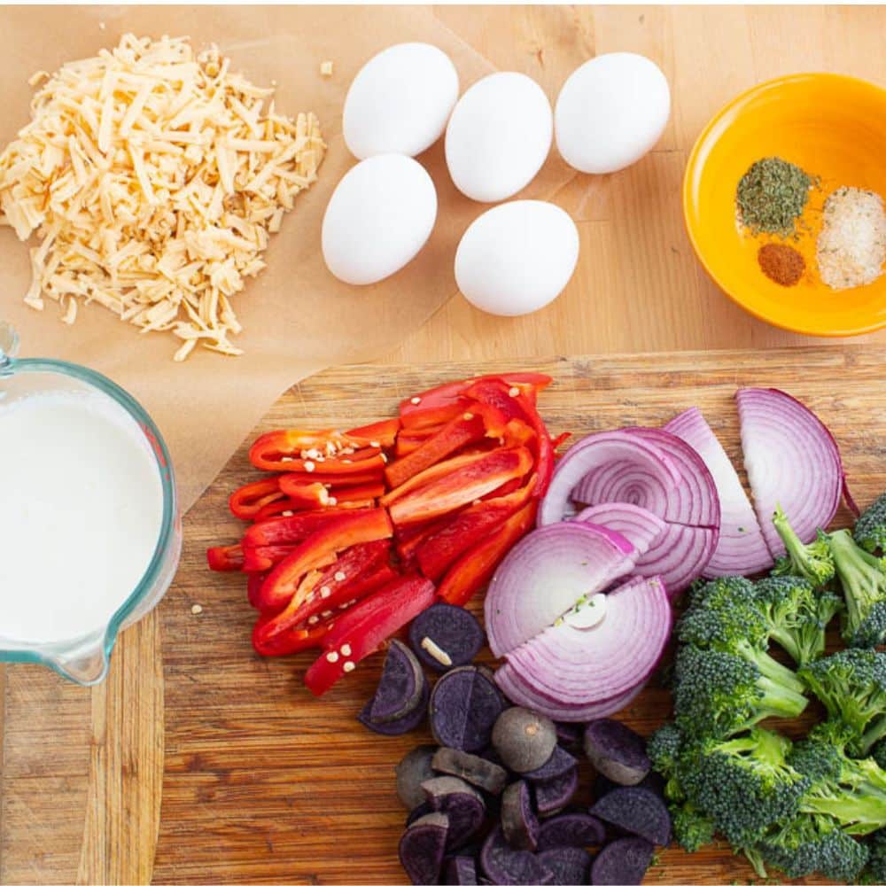 Roasted vegetable quiche ingredients on a wood cutting board.